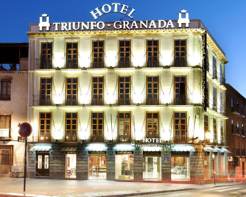 um grande edifício branco com um cartaz em Exe Triunfo Granada em Granada