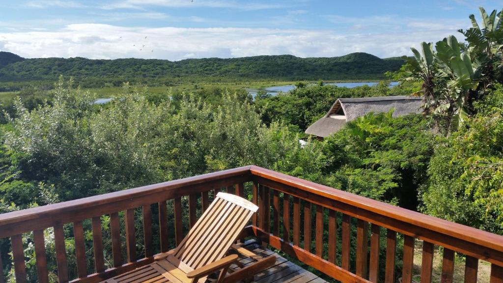 a wooden deck with a chair sitting on top of it at House 53 Sodwana Bay Lodge in Sodwana Bay