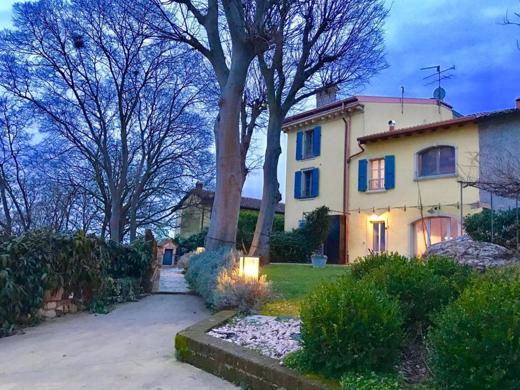 a large house with a tree in the yard at La Piana in Monzambano