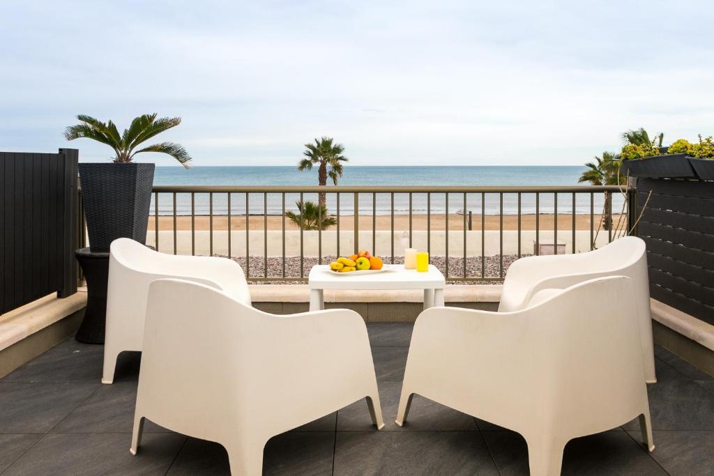 - un balcon avec une table et des chaises et la plage dans l'établissement ApartUP Patacona Terrace Duplex II, à Valence