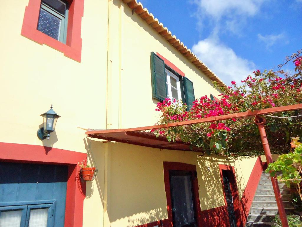 une maison avec des fleurs sur son côté dans l'établissement Casal São João Cottages 106, à Fajã da Ovelha