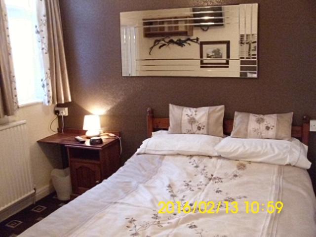ブラックプールにあるSeaforth Guest House - Pleasure Beachのベッドルーム1室(ベッド1台、ランプ付きテーブル付)
