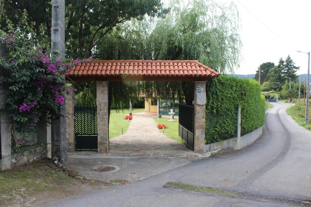 an entrance to a gate with a red roof at Chalet privado playa in Noya