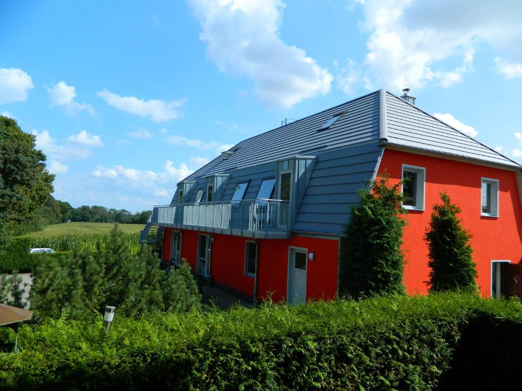 une maison rouge avec un toit métallique sur un champ dans l'établissement FEWOTRAUM-MÜRITZ, à Röbel