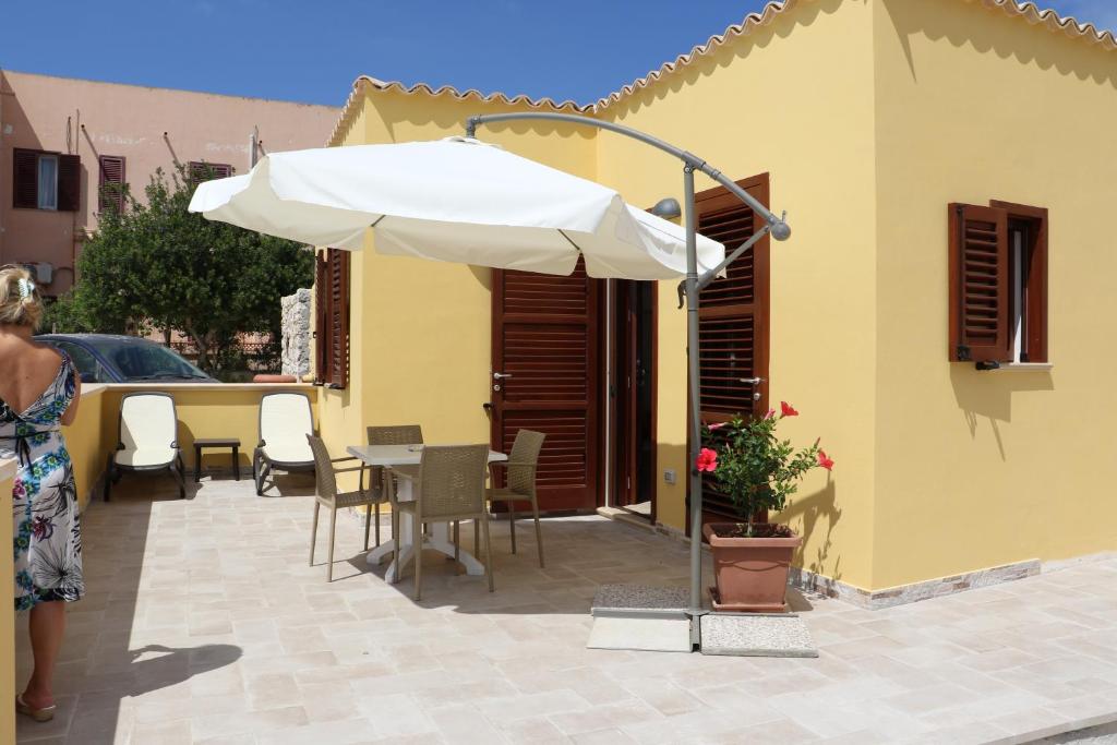 eine Terrasse mit einem Sonnenschirm, einem Tisch und Stühlen in der Unterkunft Casette D'amore in Lampedusa