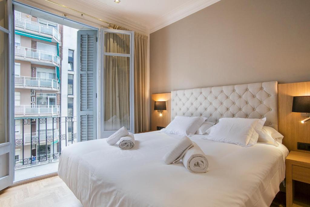 a bedroom with a white bed with a large window at Tendency Sagrada Familia Luxury in Barcelona