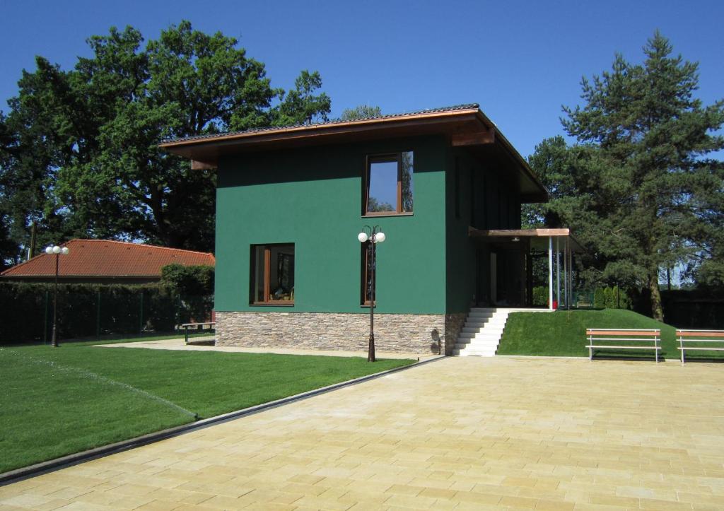 a green building with two benches in front of it at Apartmány v rodinném domě in Hluboká nad Vltavou