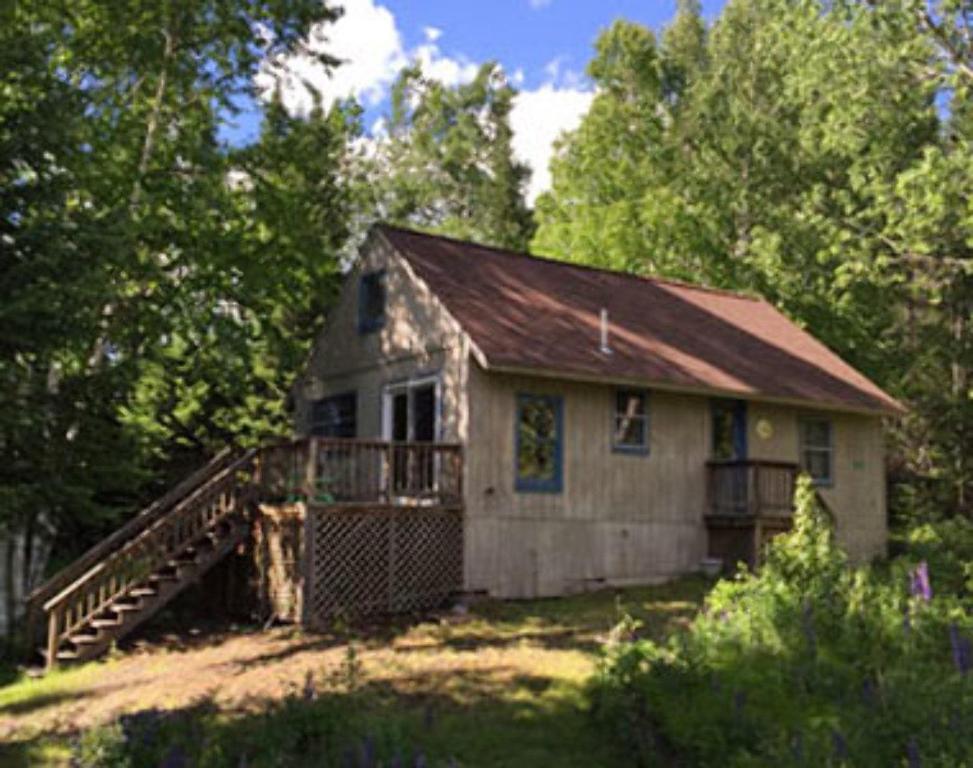 a small house with a porch and a staircase at Camp Mitigwa Rental in Rangeley