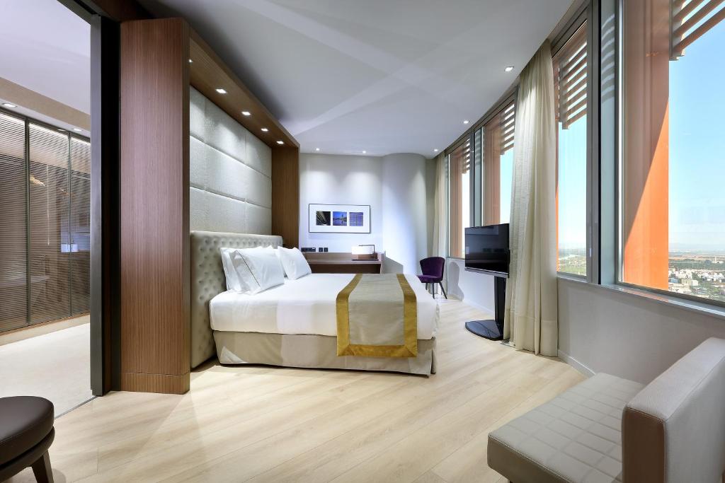 a hotel room with a bed and a desk and windows at Eurostars Torre Sevilla in Seville