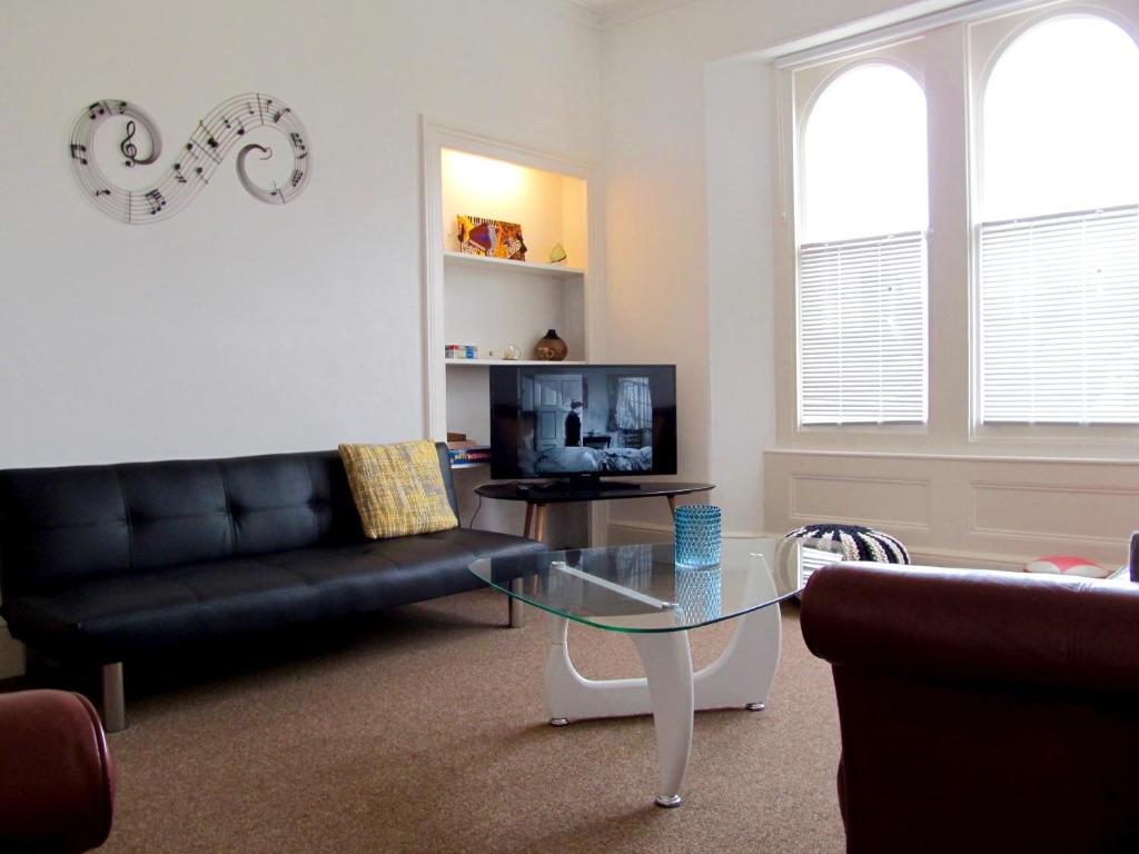 a living room with a black couch and a glass table at The Beatnik, Victorian townhouse apartment with parking in Plymouth