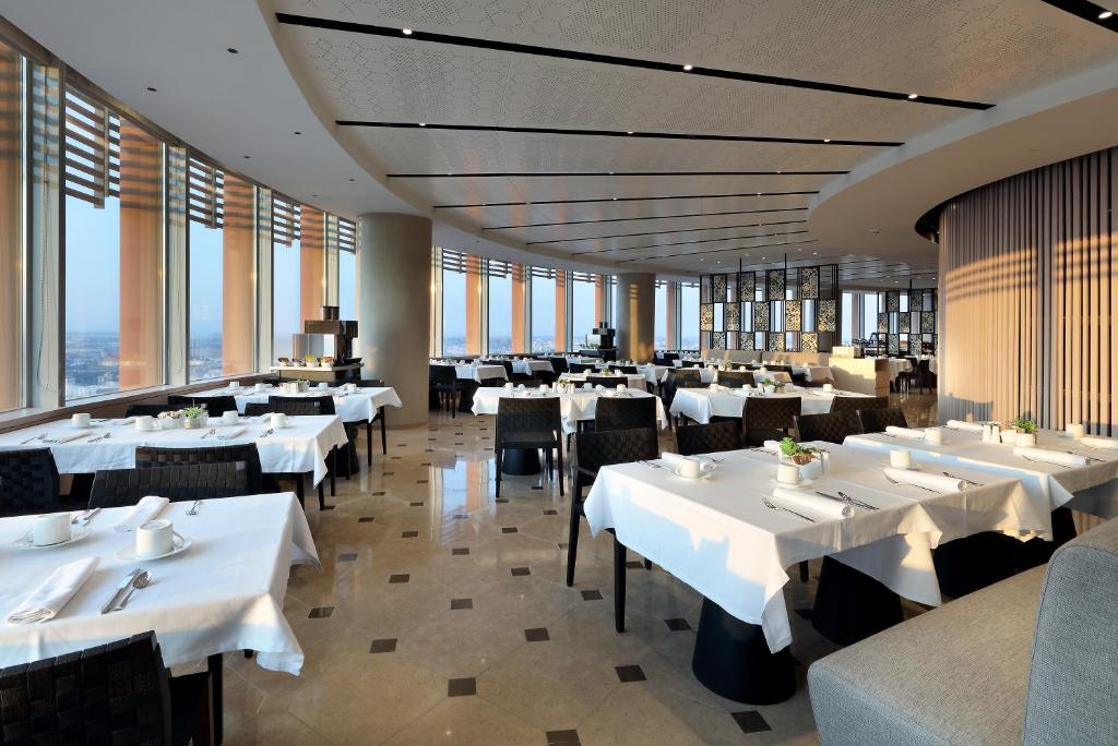 a restaurant with white tables and chairs and windows at Eurostars Torre Sevilla in Seville