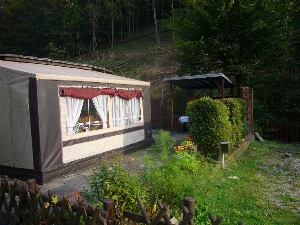 a small house with a window in a garden at Mietwohnwagen in Lonau