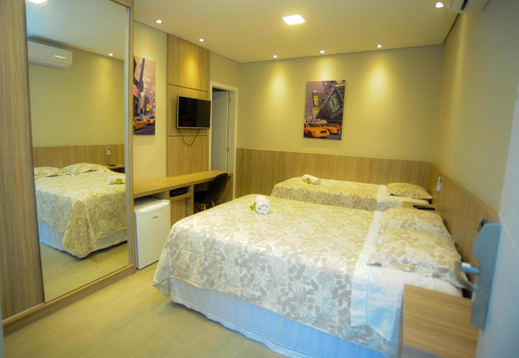 a hotel room with two beds and a mirror at Cynn Hotels in São José dos Campos