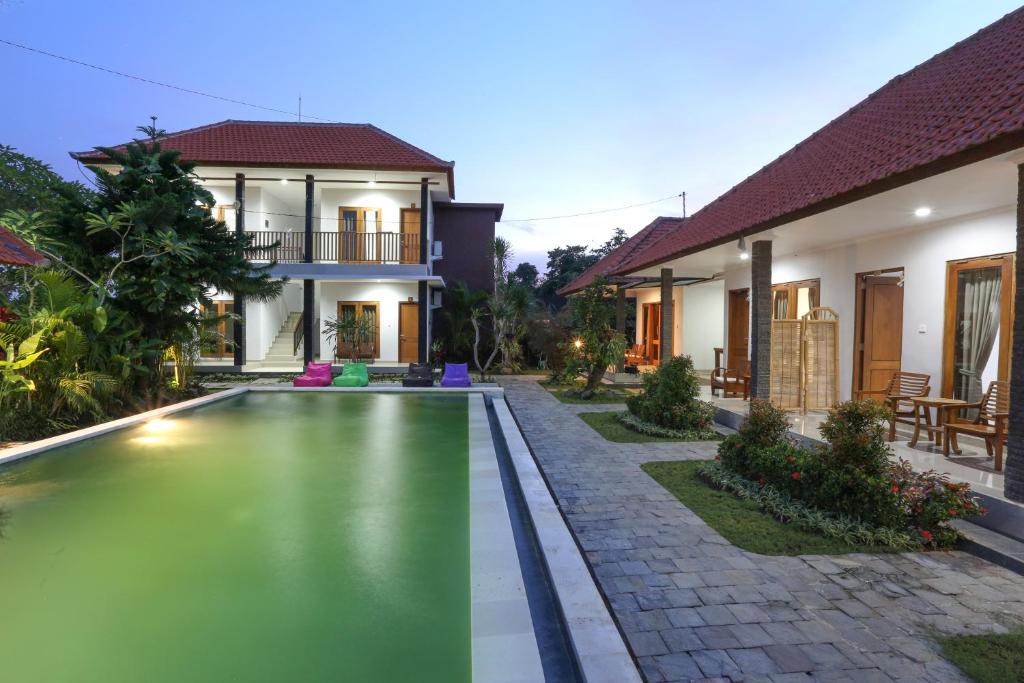 a villa with a swimming pool in front of a house at Green Papaya House in Ubud