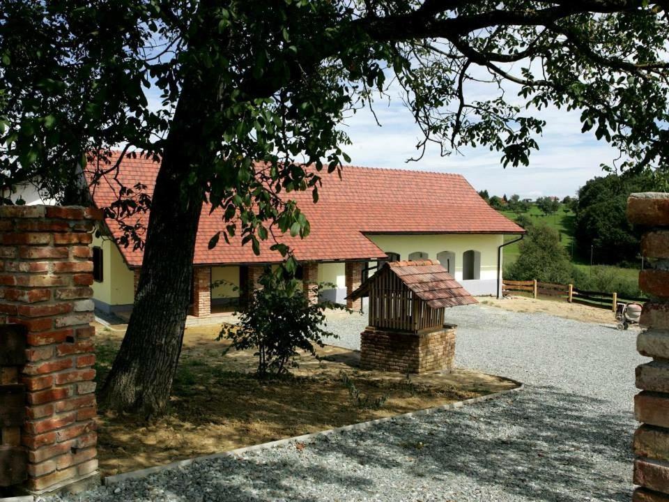 a house with a tree and a brick wall at Apartments Mali Raj in Dolenci