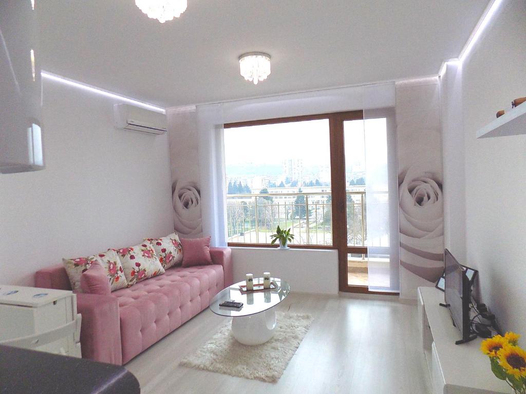 a living room with a pink couch and a table at Apartment Silvi in Varna City