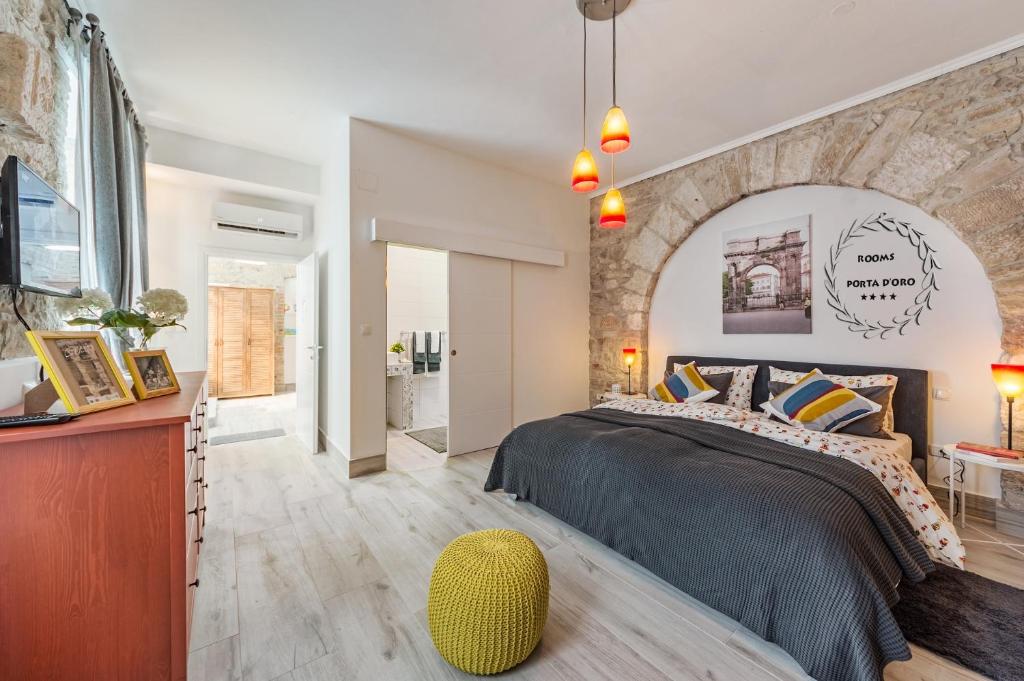 sypialnia z dużym łóżkiem i kamienną ścianą w obiekcie Porta d'Oro rooms w Puli
