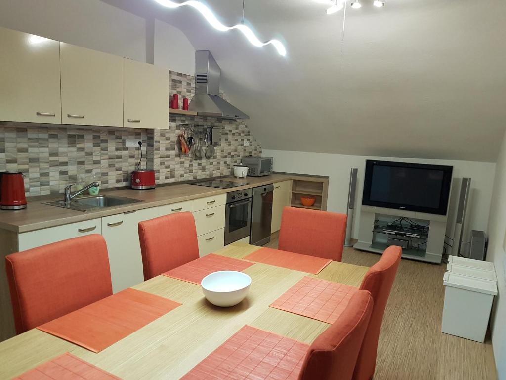 une cuisine avec une table et des chaises orange ainsi qu'une télévision dans l'établissement Apartmán 101, à Horní Maršov
