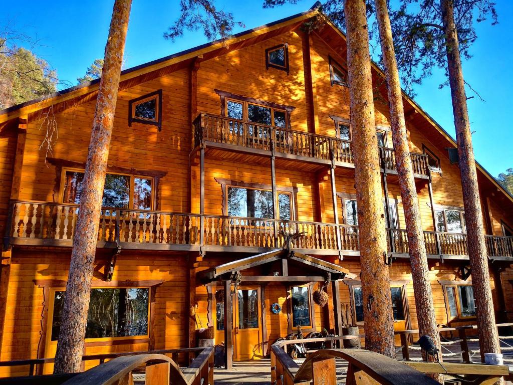 a large wooden house with a balcony and trees at Chalet Turgoyak Guest House in Turgoyak