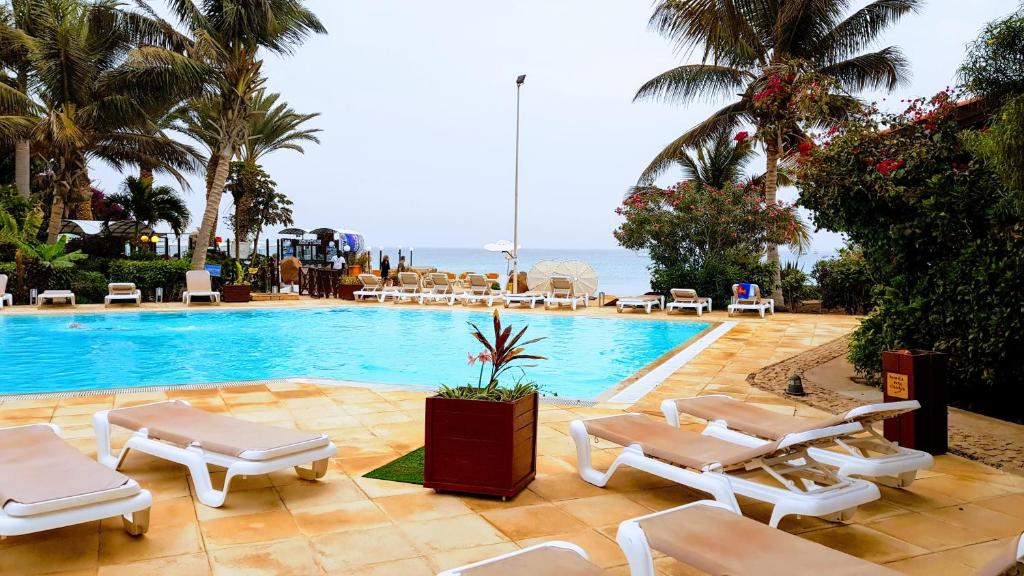 a swimming pool with chaise lounge chairs and the ocean at Porto Antigo 2 BeachFront in Santa Maria