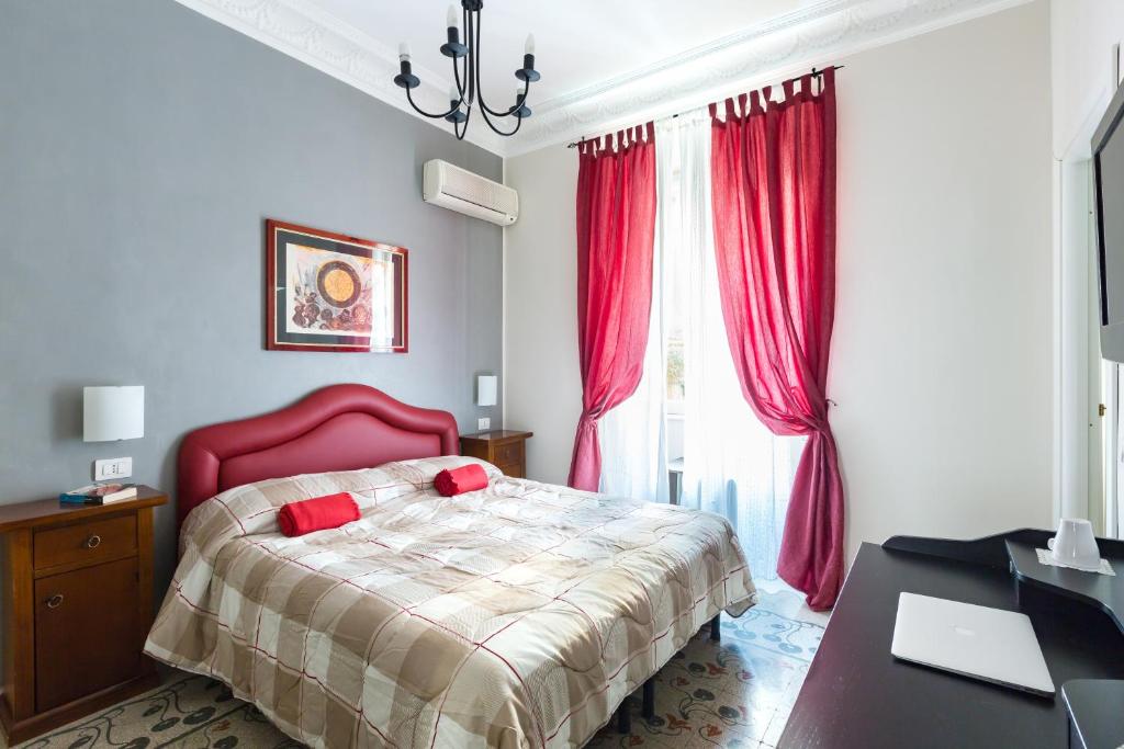 a bedroom with a bed with red curtains and a desk at B&B Calamatta in Rome