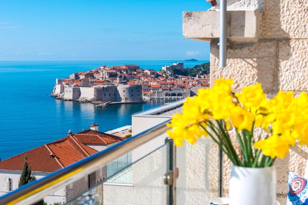 un jarrón de flores amarillas en un balcón con vistas en Two Palm Trees Apartment, en Dubrovnik