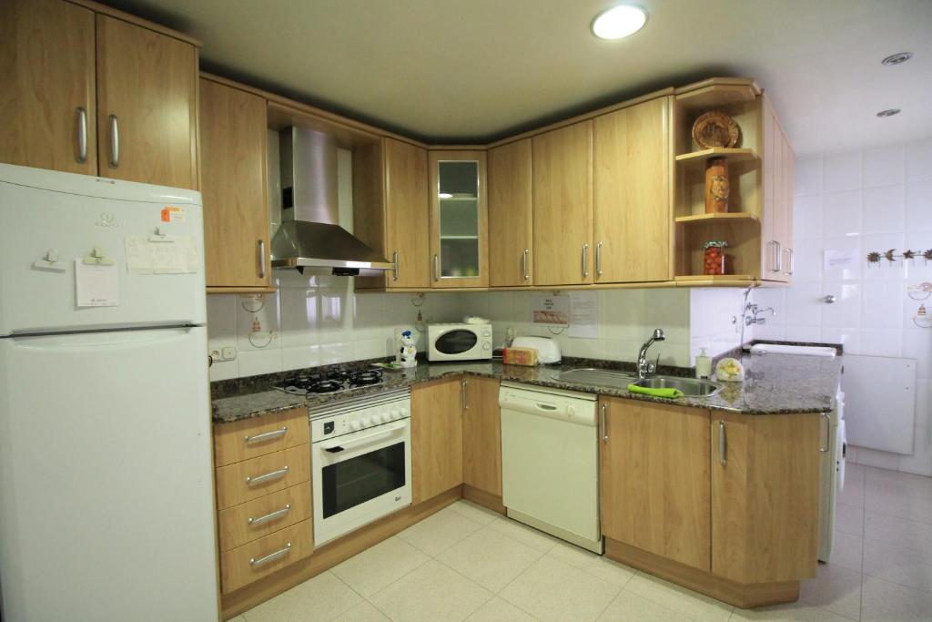 a kitchen with wooden cabinets and a white refrigerator at Piso Vacacional en Murcia in Beniaján