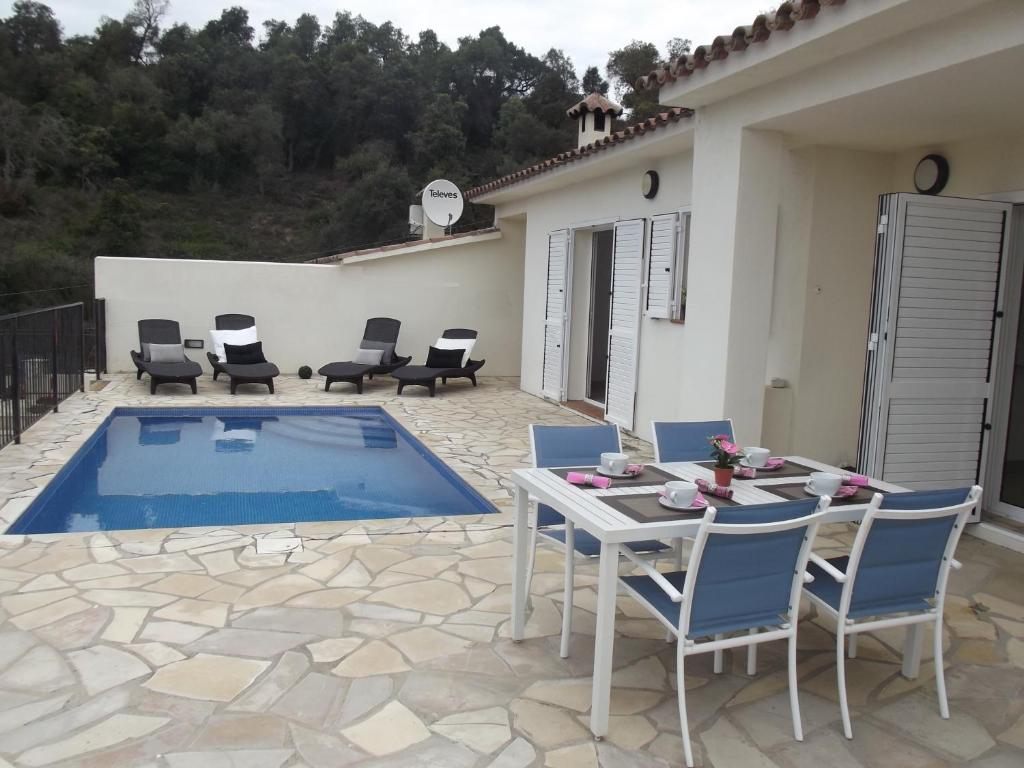 un patio con mesa, sillas y piscina en DANLUX MOLI 13, en Tossa de Mar