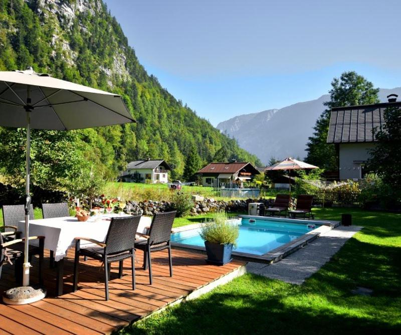 a patio with a table and an umbrella next to a pool at B&B Haus Hemetzberger in Hallstatt