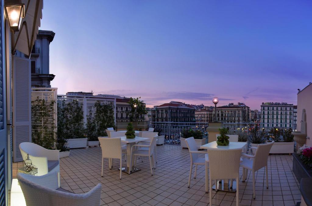 un patio con mesas y sillas en el balcón en The Five Rooms Napoli en Nápoles