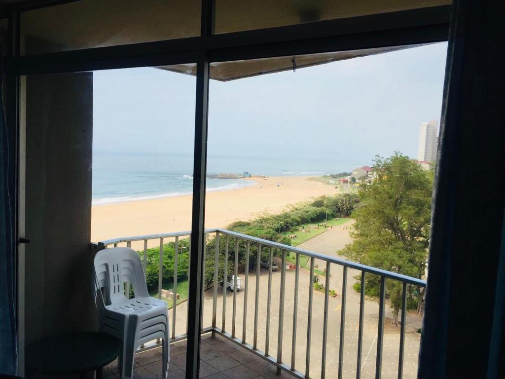 a room with a balcony with a view of a beach at Strandburg Holiday Apartments in Amanzimtoti