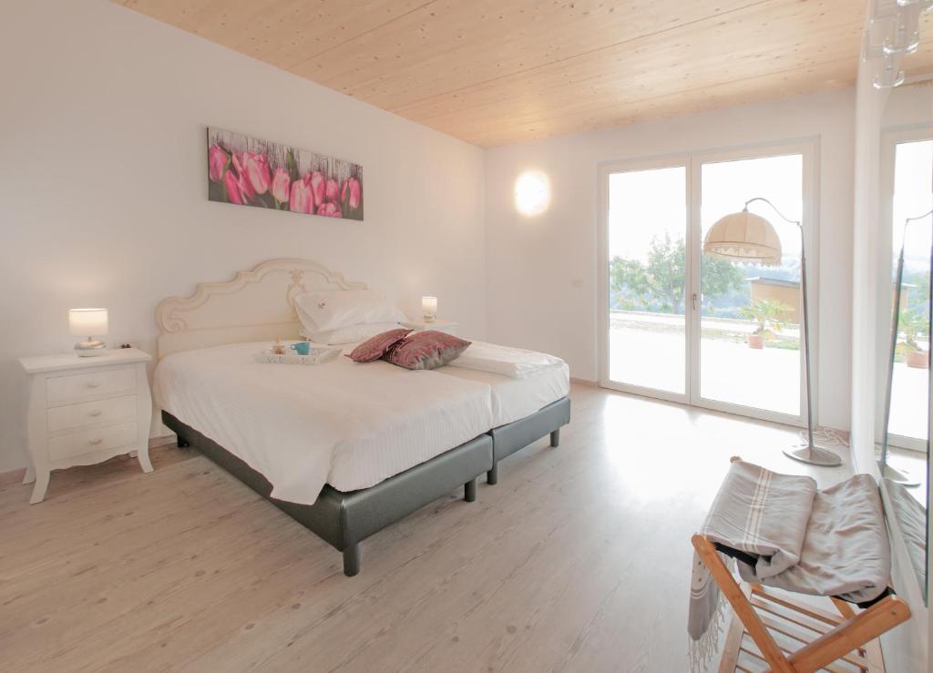 Agriturismo Monte Oliveto في باردولينو: غرفة نوم بيضاء بسرير وكرسي