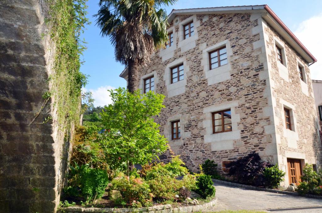 un antiguo edificio de piedra con una palmera en Casa da Capilla, en Gres