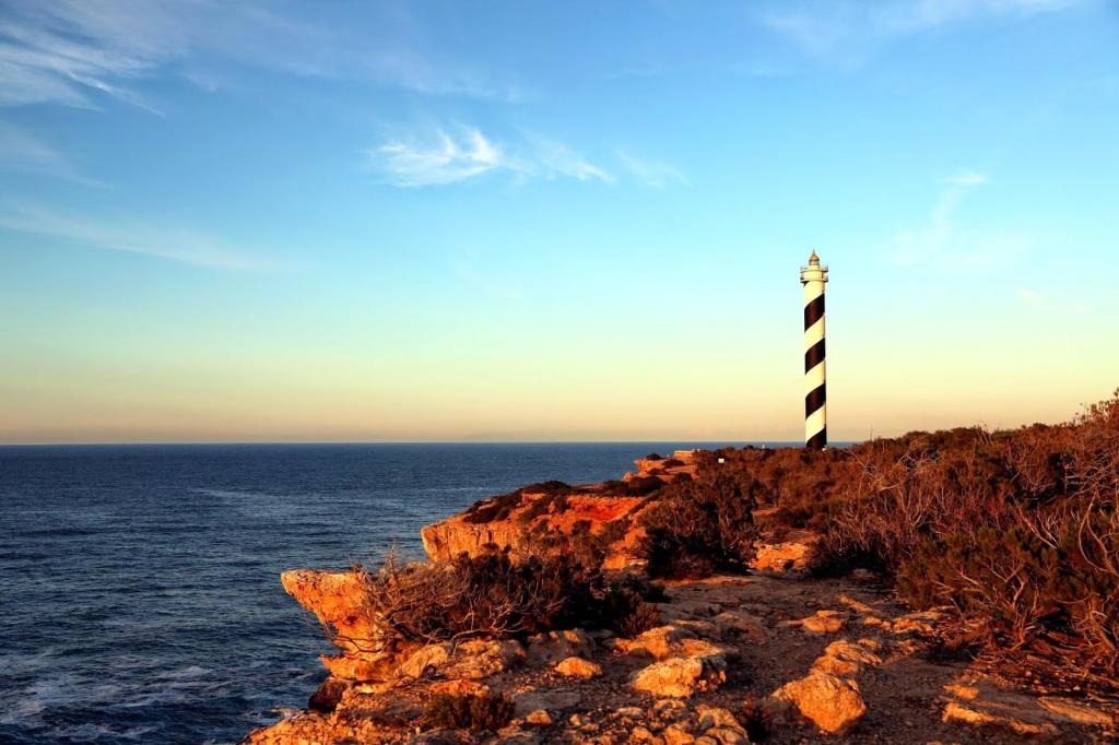 a lighthouse on the edge of a cliff near the ocean at Granada Apartments Familiar Deluxe in Portinatx