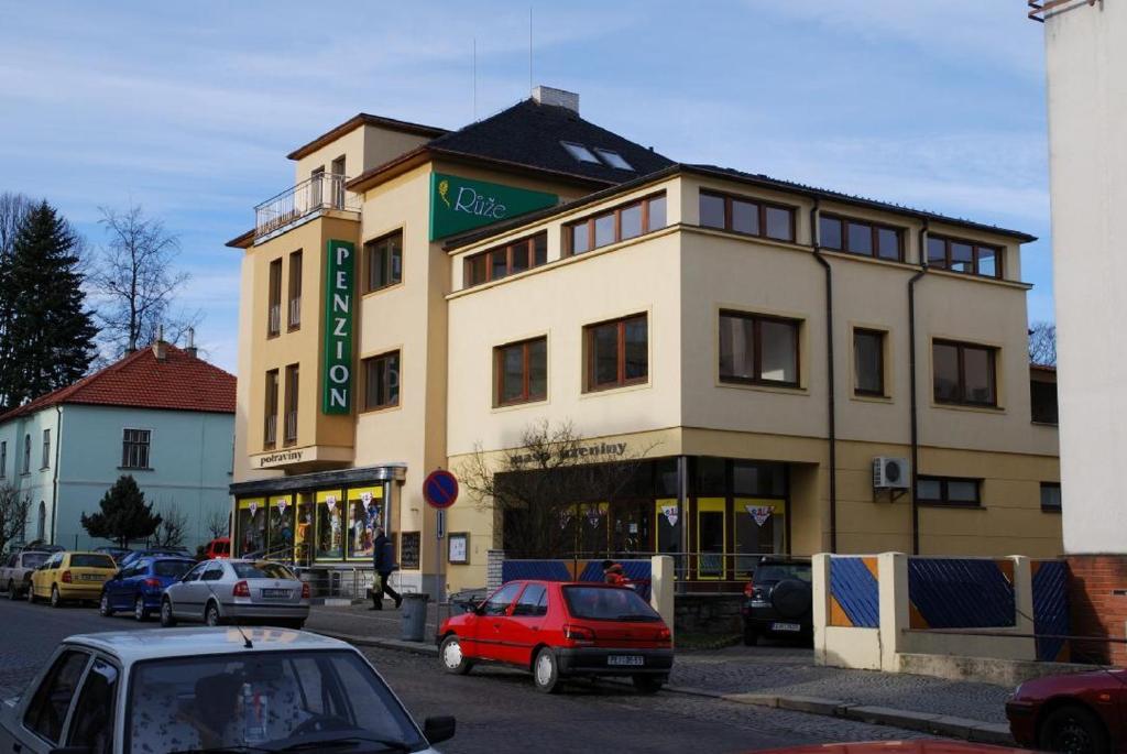 un gran edificio con coches estacionados frente a él en Penzion Růže, en Humpolec