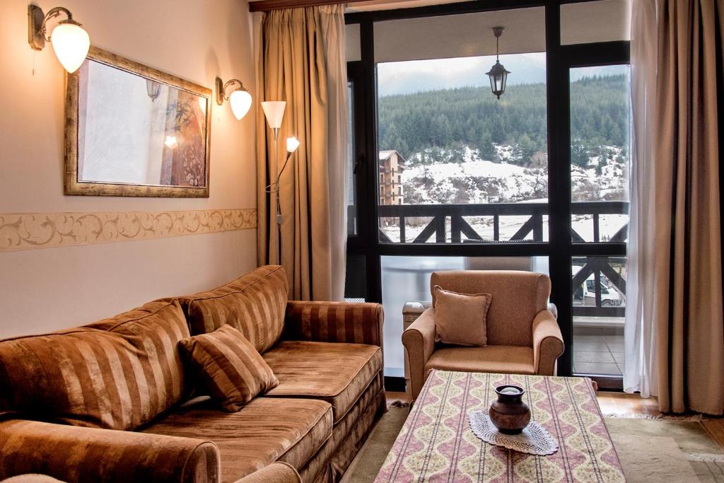 バンスコにあるCozy Suite in 5* Luxury Spa Hotelのリビングルーム(ソファ、椅子、窓付)
