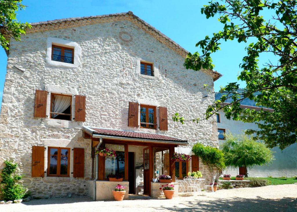 un gran edificio de piedra blanca con ventanas de madera en La ferme du Château en Saint-Martin-en-Vercors