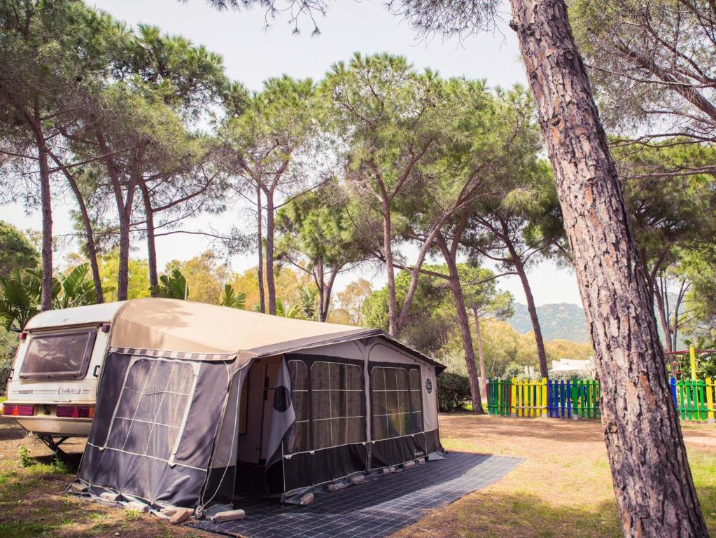 a tent parked in a field next to a tree at Camping Cala d'Ostia in Pula