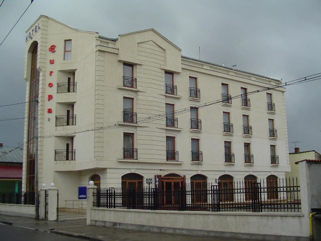 a white building with a fence in front of it at Hotel Europa in Ploieşti