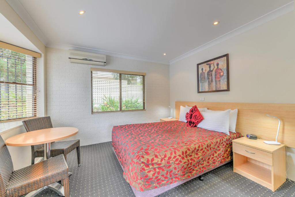 a hotel room with a bed and a desk and a table at Motel Grande in Tamworth