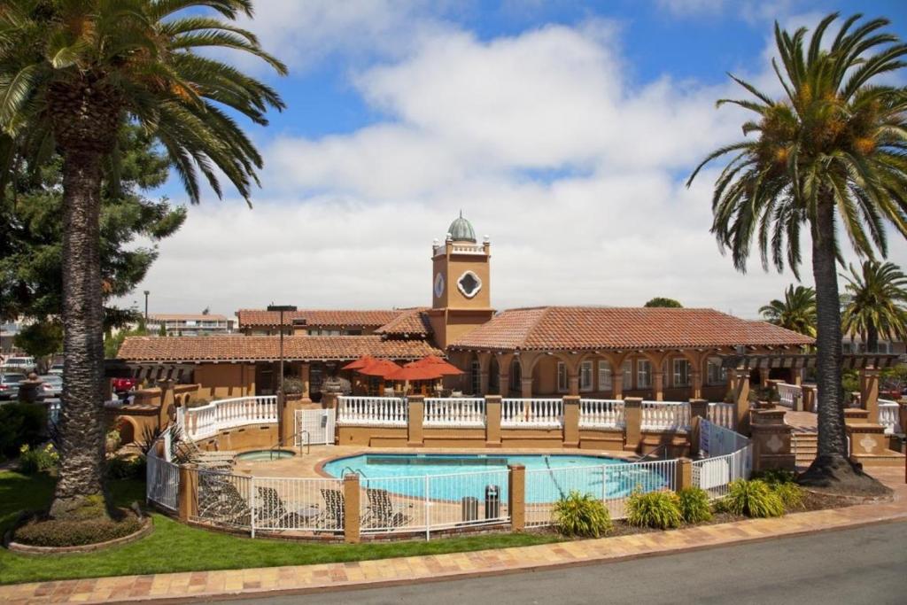 a resort with a pool and a clock tower at SFO El Rancho Inn SureStay Collection by Best Western in Millbrae