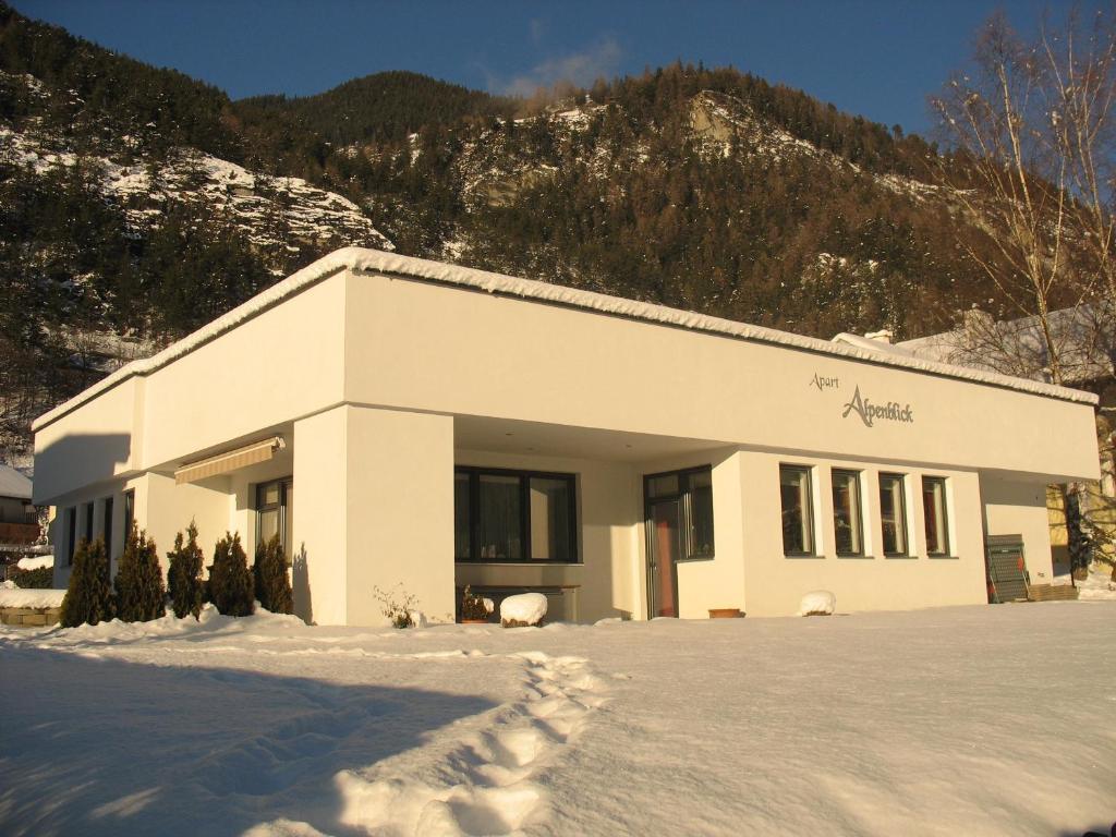 a building in the snow in front of a mountain at Apart Alpenblick in Pfunds