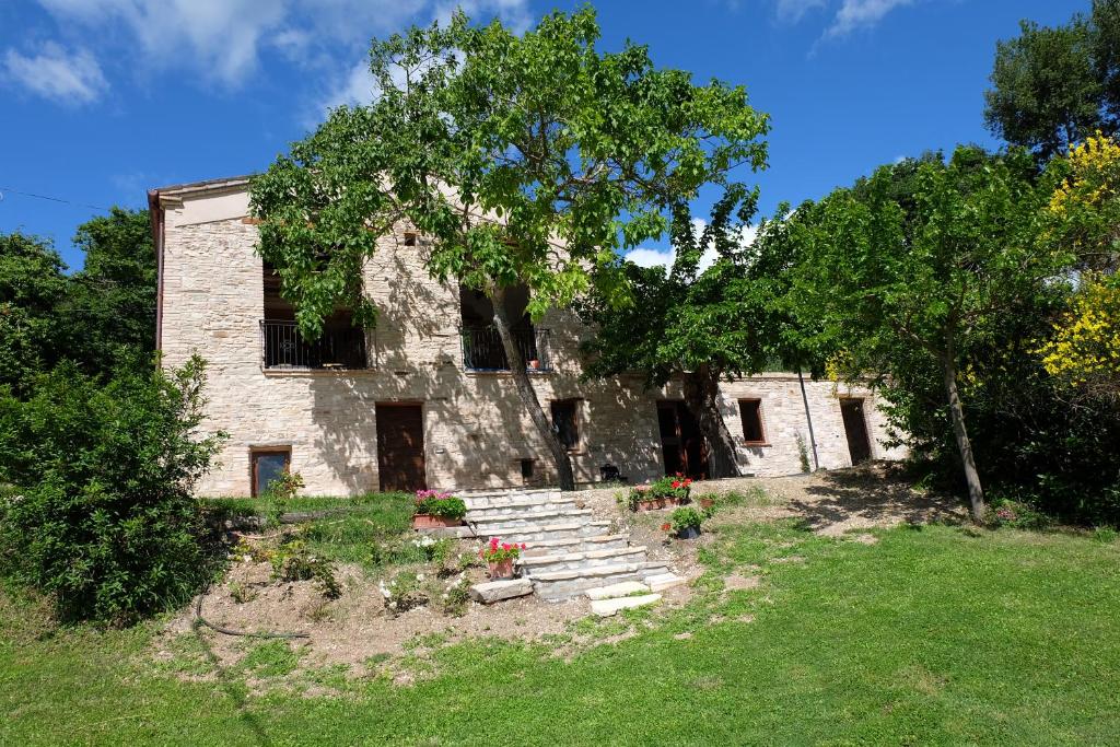 un antiguo edificio de piedra con escaleras y un árbol en Agriturismo Bosimano, en Arcevia