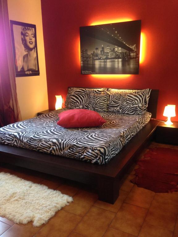 a bed with a red pillow and two lamps at Le Case di Cinzia in Vinci
