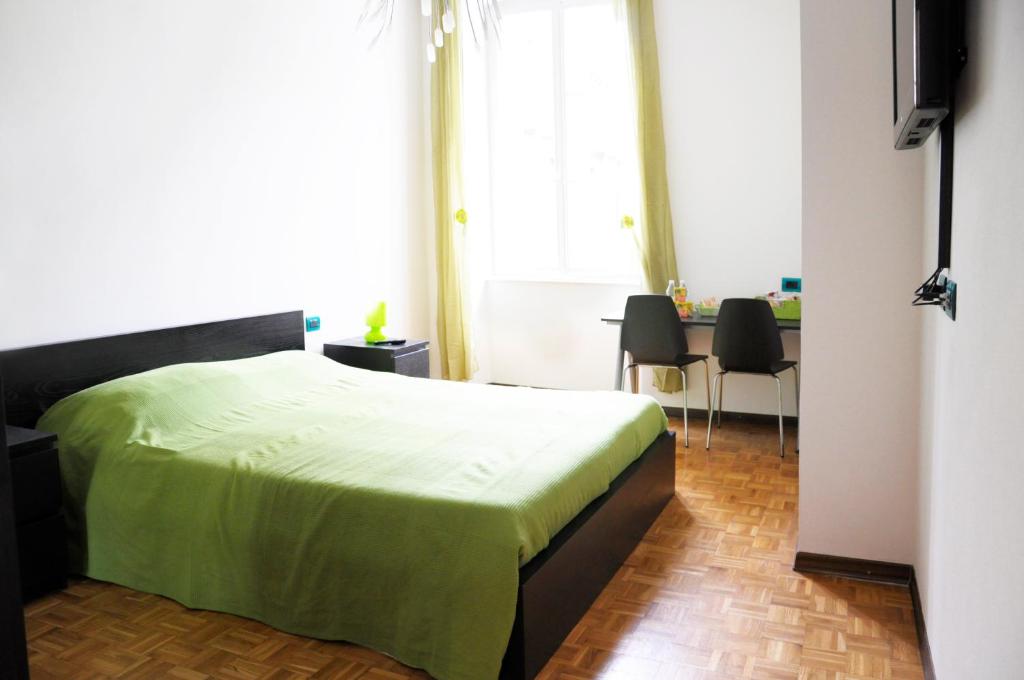 a bedroom with a bed with a green blanket on it at B&B Trieste Plus in Trieste