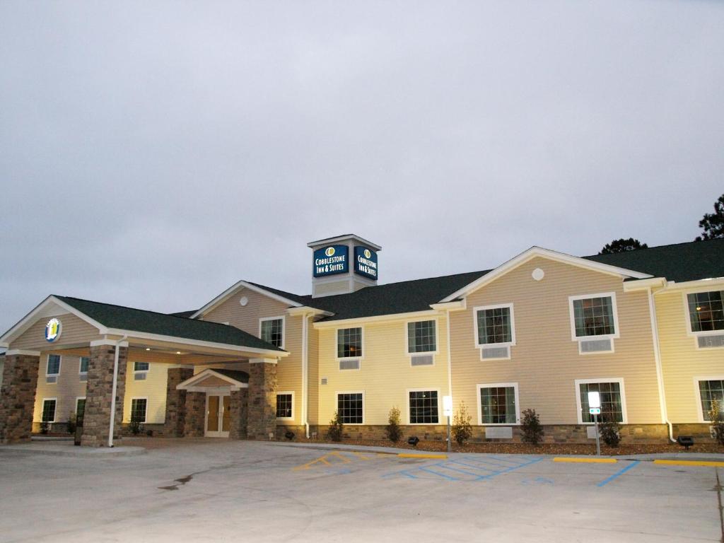 Cobblestone Inn & Suites - Vinton, LA في فينتون: مبنى أصفر كبير مع برج ساعة في الأعلى