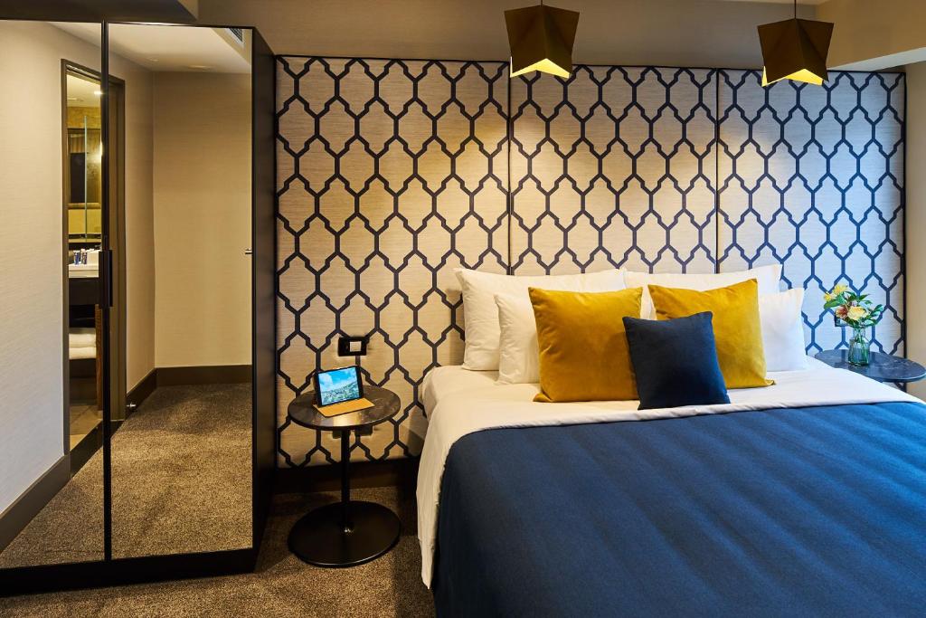 a bedroom with a large bed with a blue blanket and yellow pillows at Bolton Hotel in Wellington