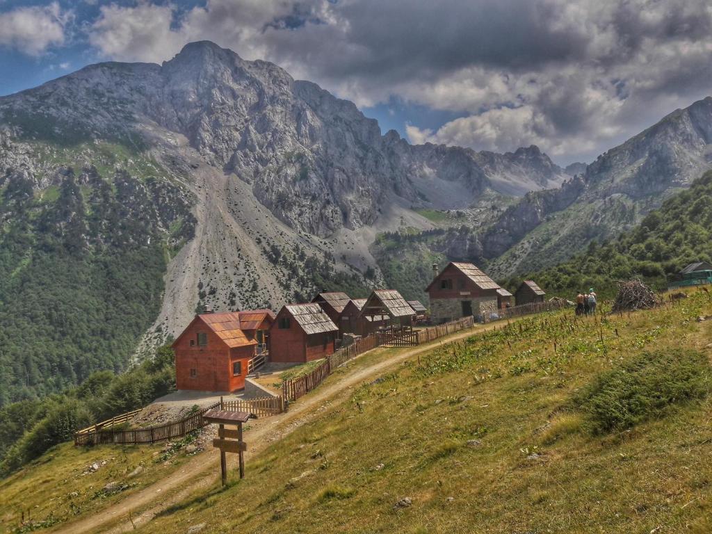 un grupo de casas en una colina con montañas en el fondo en Komovi Eko Katun Martinovica 1750, en Kolašin