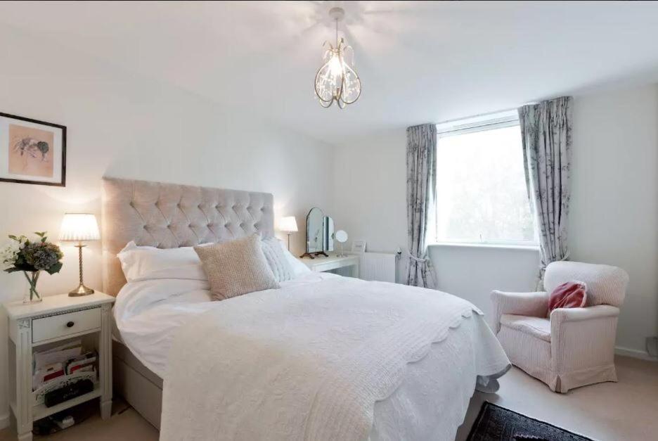a white bedroom with a large bed and a chair at Wyatt Court in London