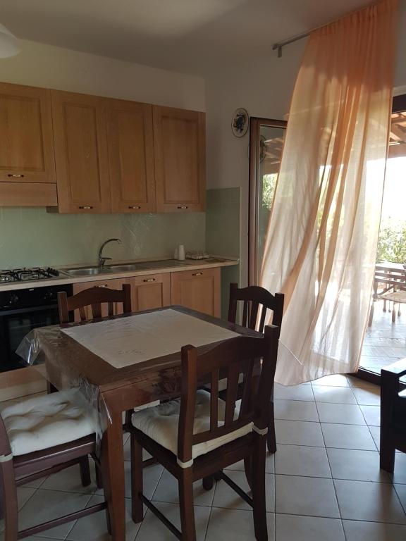 una cucina con tavolo, sedie e finestra di Zefiro Casa Vacanze ad Ascea